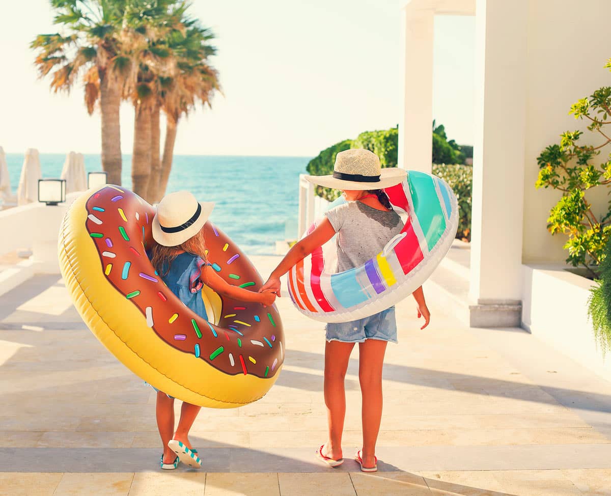 Two small girls with inflatable toys on the beach